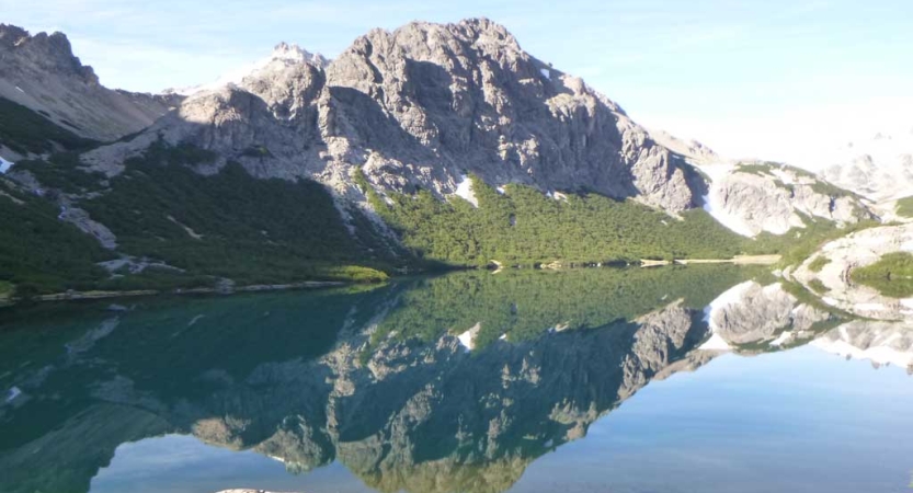 A mountain is reflected in the still water of an alpine lake. 